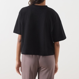 Model wearing Barbour International black cotton T-shirt, boxy cropped fit, short sleeves, back view, styled with taupe trousers.