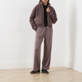 Model wearing Barbour International black T-shirt styled with mauve zip-up jacket and wide-leg trousers, black flat shoes