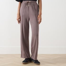 Model wearing Barbour International Truffle trousers with drawstring waist, wide-leg silhouette, styled with dark slip-on shoes