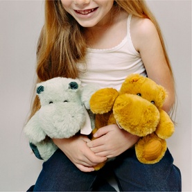 Model with Dou Dou green plush soft toy hippo and golden bear teddy, held by smiling child in white vest and jeans