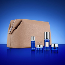 La Prairie Skin Caviar skincare gift set with five blue and silver products and a beige zip cosmetics pouch, on blue background