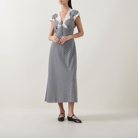 Model wearing Rixo Beth Check Black dress with lace trim neckline, midi length, styled with black ballet flats and pearl necklace.