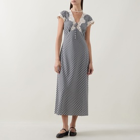 Model wearing Rixo Beth Check Black dress in monochrome gingham, midi length, frill V-neckline and cap sleeves, styled with black flat shoes.