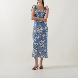 Model wearing Rixo Cathy Floral Dress in Amelia Bouquet Blue; midi-length bias cut with V-neckline, short sleeves and floral print. Styled with red