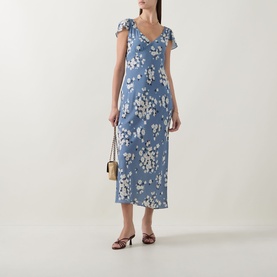 Model wearing Rixo Cathy Floral Dress in Amelia Bouquet Blue; midi-length, V-neck, short sleeves, bias cut. Styled with brown heels and gold bag.