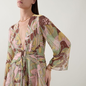 Model wearing Rixo Clove Bianca Abstract Mini Dress in Bianca Abstract Green, plunge neckline, three-quarter sleeves, draped waist tie, gold necklace
