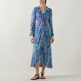 Model wearing Rixo Bianca Abstract Blue silk midi dress with ruffle V-neck, long sleeves, and wrap-style skirt, styled with flat sandals.