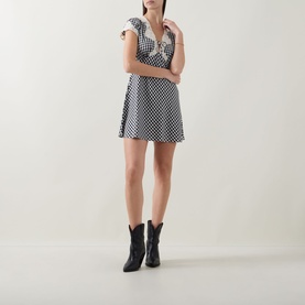 Model wearing Rixo Lacie Check Dress in black check print, mini length with V-neck tie detail and lace trim, styled with black cowboy boots.