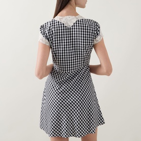 Model wearing Rixo Lacie Check Dress in black gingham with lace trim detail on short sleeves, back view showing empire waist and mini length.