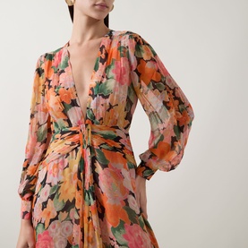 Model wearing Rixo Chelsea Floral Black dress with deep V-neckline, gathered waist detail and long blouson sleeves in vibrant floral print