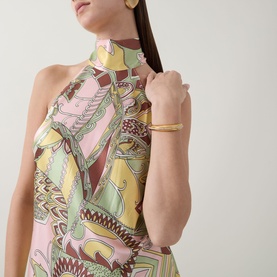 Model wearing Rixo Maura Bianca Abstract Dress in Bianca Abstract Green, halter neckband style, styled with gold earrings and bangle bracelet.