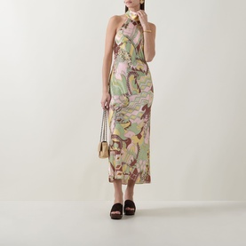 Model wearing Rixo Maura Bianca Abstract Dress in Bianca Abstract Green, halter midi style. Styled with a gold bag and dark mule sandals.