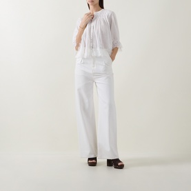 Model wearing Rixo ivory cotton top with lace trim details, styled with white wide-leg trousers and dark wood platform clogs