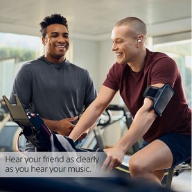 Two people laughing in a gym, one wearing Sony Linkbuds True Wireless Earbuds in White while cycling, with text overlay about hearing friends clearly.