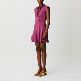 Model wearing Claude Pierlot purple sleeveless mini dress with ribbed texture and tie neck, styled with gold strappy heeled sandals.