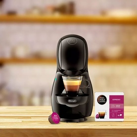 Delonghi Dolce Gusto Piccolo XS Pod Coffee Machine Bundle in black, shown with Nescaf&eacute; Dolce Gusto Espresso pods on wooden surface