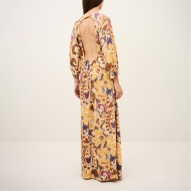 Model wearing Bash yellow floral paisley print maxi dress with open back and long sleeves, shown from behind.