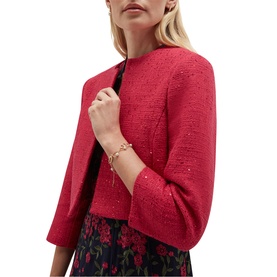Model wearing Hobbs mulberry pink sequin tweed cropped jacket with three-quarter sleeves, styled with a floral skirt and gold bracelet.