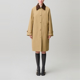 Model wearing Claude Pierlot coat in clear beige with contrast brown collar, button front, midi length, styled with grey socks and black sandals
