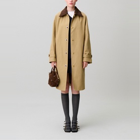 Model wearing Claude Pierlot clear longline coat with contrast collar, styled with pink dress, grey knee socks, black sandals, and brown mini bag.