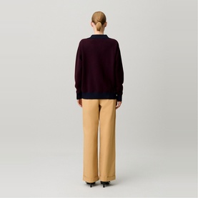Model wearing Claude Pierlot black knit sweater, back view, styled with wide-leg camel trousers