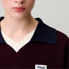 Model wearing Claude Pierlot knit top in black with contrast navy collar, cream V-neck ribbed panel and script logo patch, close-up detail shot.