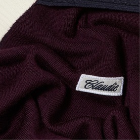 Claude Pierlot woven label detail on black and burgundy knit fabric, showing brand branding at close range