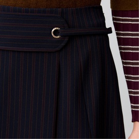 Claude Pierlot black pinstripe wide-leg trousers with wrap-front detail and gold-tone buckle belt, styled with striped top