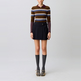 Model wearing Claude Pierlot black mini skirt with belt detail, styled with striped knit polo top, knee-high socks and flat sandals
