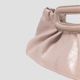 Maje bag in mastic beige patent leather with ruched detail and structured top handle, close-up view