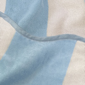 Allure Scallop Beach Towel in ice blue and white wide stripe jacquard cotton, close-up showing texture and scalloped edge detail.