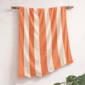 Allure Scallop Beach Towel in orange and cream vertical stripes, 100% cotton, hanging from a wooden rod.