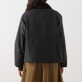 Model wearing Barbour waxed cotton jacket in Shadow Classic, rear view, with brown corduroy collar, styled with khaki wide-leg trousers