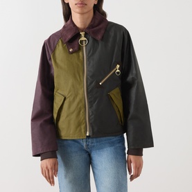Model wearing Barbour jacket in Golden Olive/Fern colourblock with burgundy, olive and black panels, gold zip and ring hardware, styled with blue