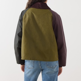 Model wearing Barbour jacket in Golden Olive/Fern colourblock waxed cotton, rear view, styled with light blue jeans