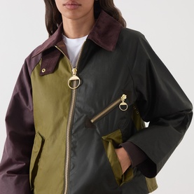 Model wearing Barbour waxed cotton jacket in Golden Olive/Fern colourblock with burgundy collar and gold ring-pull zip detail