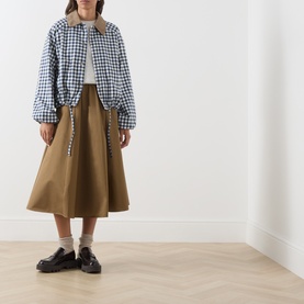 Model wearing Barbour Gingham Navy/Neutral jacket with tan midi skirt, white socks and black loafers