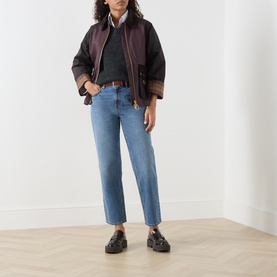 Model wearing Barbour mid blue straight-leg jeans with dark jacket, grey top and black chunky loafers