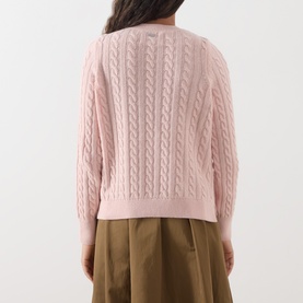 Model wearing Barbour Ashdown Cable-Knit Sweater in Pink Blush, showing cable-knit back detail and long sleeves, styled with khaki wide-leg trousers.