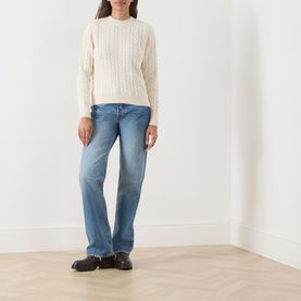 Model wearing Barbour Ashdown Cable-Knit Sweater in ecru with blue straight-leg jeans and dark loafers.