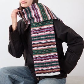 Model with Barbour Scottish Fairisle Scarf in multi, featuring Fair Isle knit pattern in green, pink and white tones, styled over dark jacket.