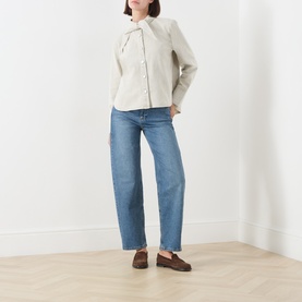 Model wearing Barbour Harleigh Tie-Neck Denim Shirt in Washed Birch with blue straight-leg jeans and brown loafers.