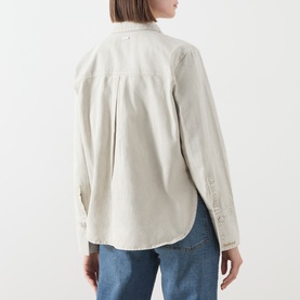Model wearing Barbour Harleigh Tie-Neck Denim Shirt in Washed Birch, showing rear box pleat and curved hem, styled with blue jeans.