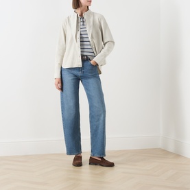 Model wearing Barbour Harleigh Tie-Neck Denim Shirt in Washed Birch with blue wide-leg jeans and striped top underneath.