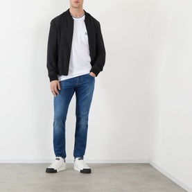 Model wearing Dolce & Gabbana Straight Leg Jeans in mid blue with whiskering detail, styled with black bomber jacket and white tee.