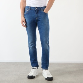 Model wearing Dolce & Gabbana Straight Leg Jeans in mid blue with whiskering and faded details, styled with white trainers.
