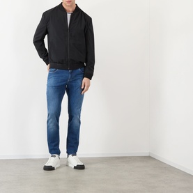 Model wearing Dolce & Gabbana Straight Leg Jeans in blue with whiskering and faded details, styled with a black bomber jacket and white trainers.