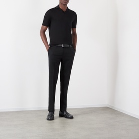 Model wearing Dolce & Gabbana black cotton jeans with a black polo shirt and leather belt, styled with loafers.