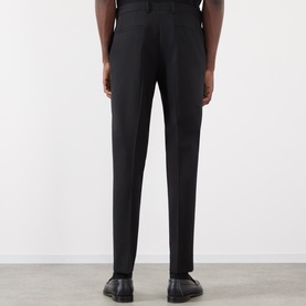 Model wearing Dolce & Gabbana black cotton trousers, rear view, slim tailored fit, styled with black leather shoes.