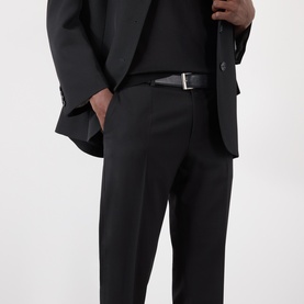 Model wearing Dolce & Gabbana black cotton jeans with a tailored black blazer and silver-buckle belt.